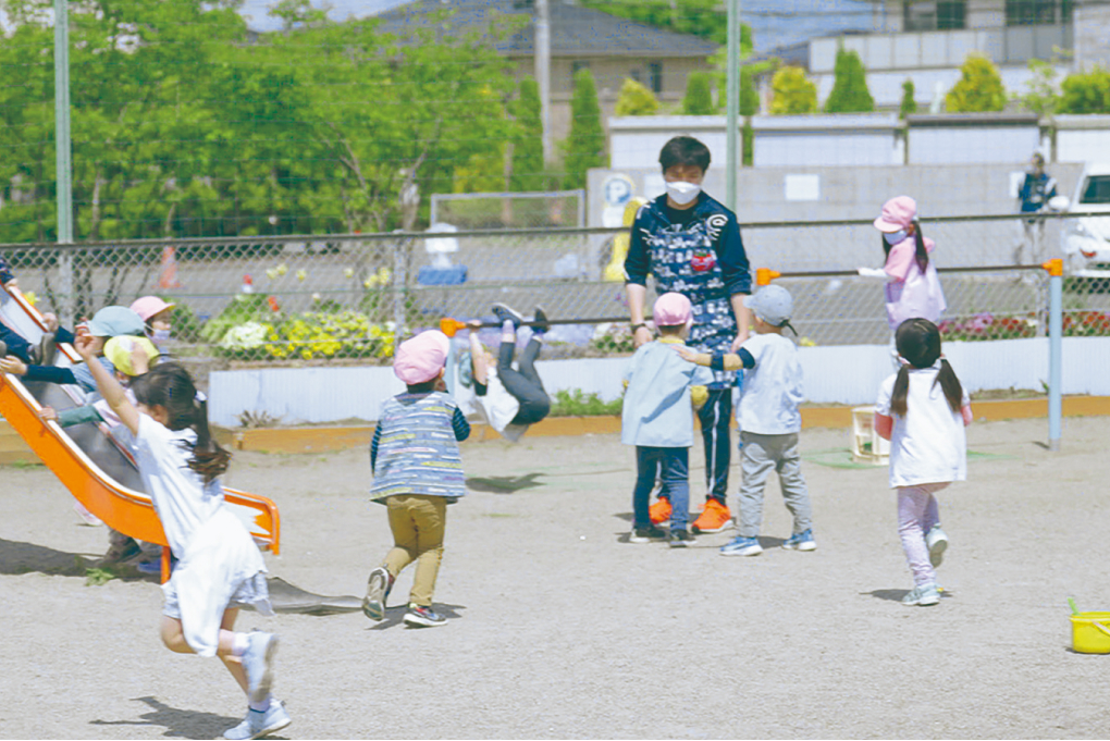 園庭で子供たちと遊ぶ様子の写真