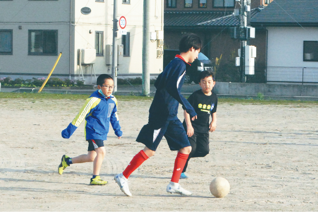 小学生とサッカーをする様子の写真