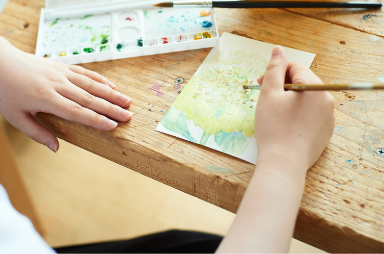 学生が絵の具で絵を描いている様子の写真