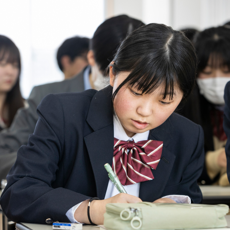 机に向かって勉強する女子学生の写真