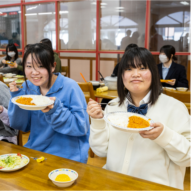 食堂でカレーを食べる女子学生2人の写真