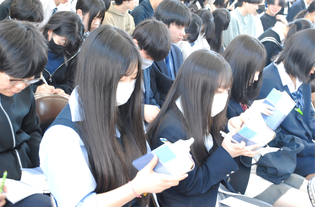 体育館で立って聖書を読む学生たちの写真（小2）